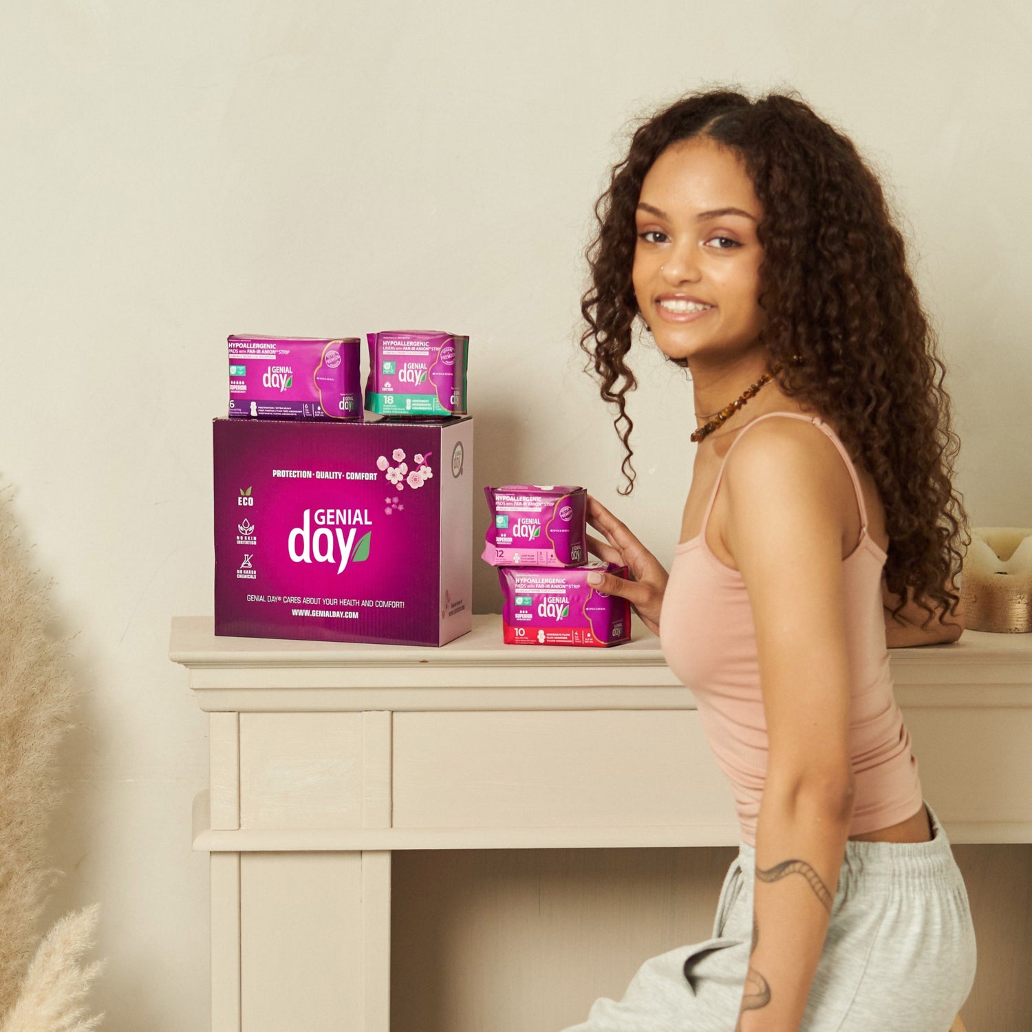 Woman sitting on a stool next to a desk with Genial Day boxes on it