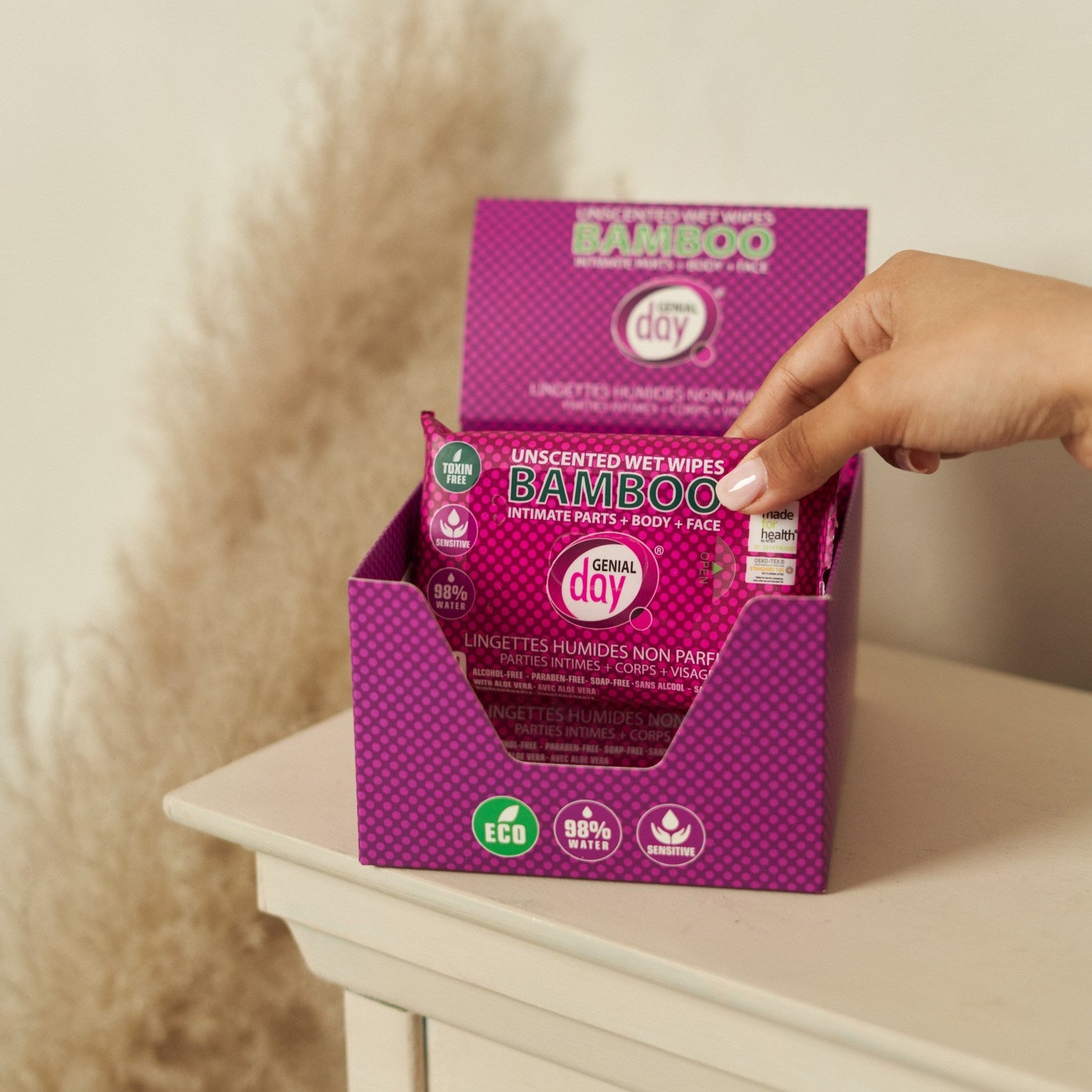 Hand reaching for a box of Bamboo wet wipes on a white surface with a neutral background