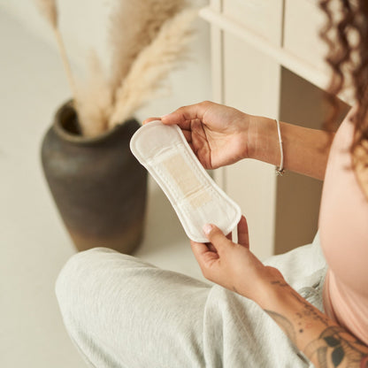 Person holding a menstrual pad in a home setting